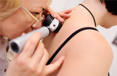 [Translate to Deutsch:] Physician looking on skin of patient with an miscroscope instrument