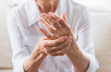 [Translate to Deutsch:] Person in white blouse holding left hand with right hand